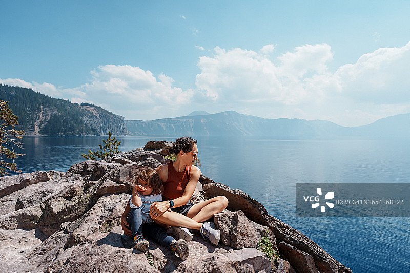 充满活力的母亲和幼儿女儿在徒步旅行时欣赏山 Lake 美景图片素材