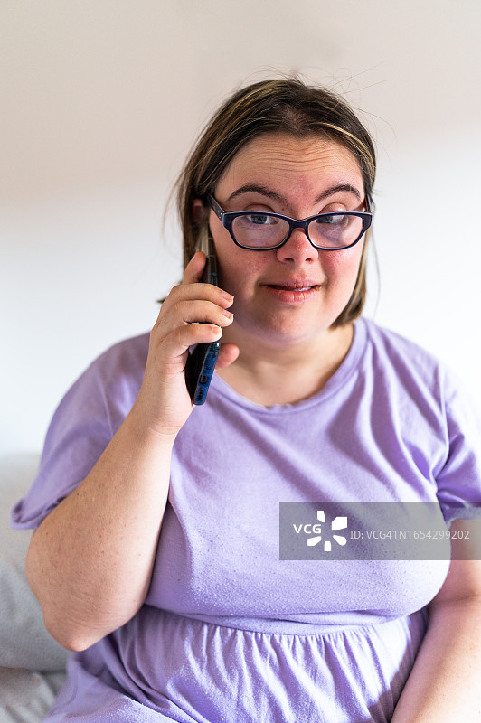 患有唐氏综合征的女人在家用手机聊天图片素材
