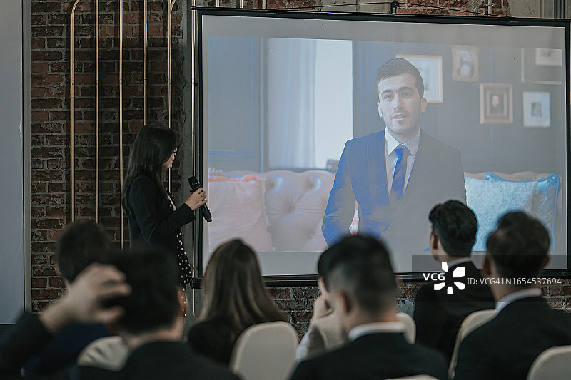 亚洲商务人士在会议室通过投影仪屏幕进行视频会议。多元化的创意企业家团队在研讨会上进行讨论。专家在数字电子商务创业公司工作图片素材