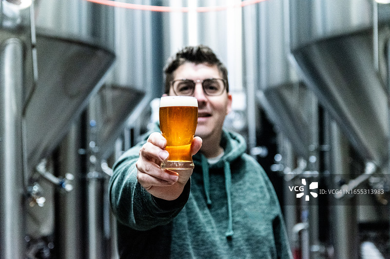 中年男人在啤酒厂手持啤酒杯特写图片素材