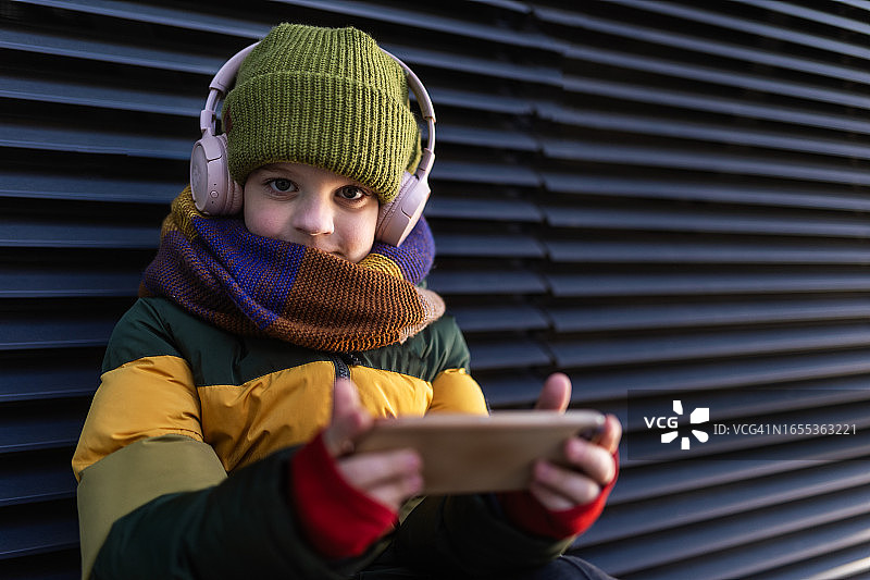 寒冬城市里玩手机游戏的可爱儿童图片素材