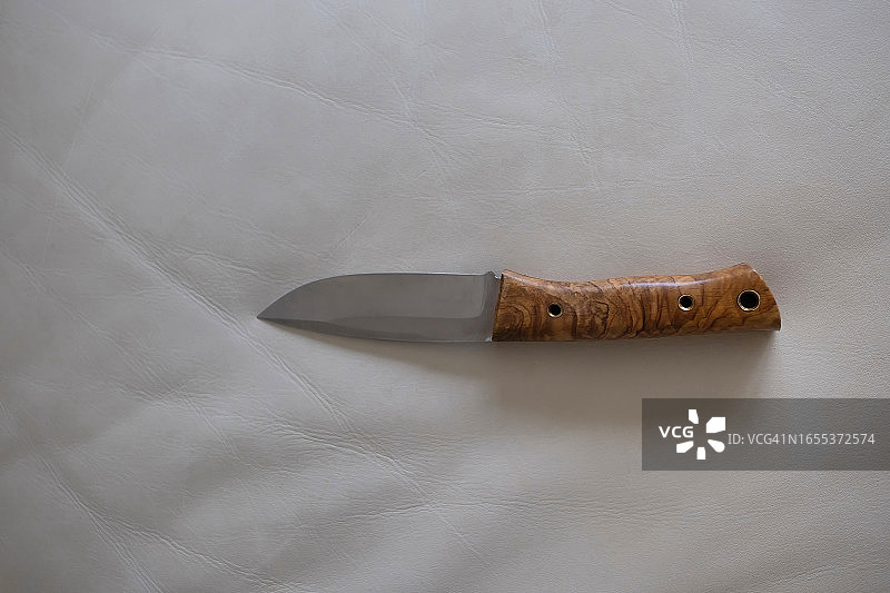 皮革沙发上带木柄的多功能刀图片素材