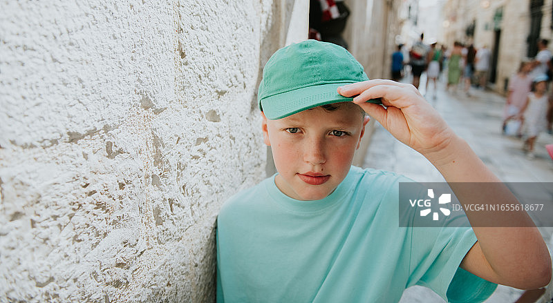 站在户外触摸帽子边缘的年轻人图片素材