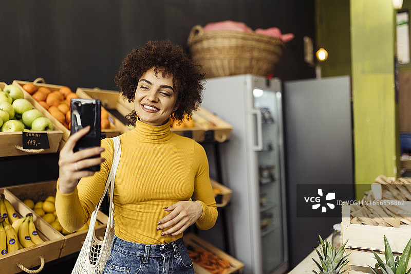 一位年轻的非裔美国女性在杂货店购物，手提购物篮，正在阅读瓶子上的成分标签图片素材