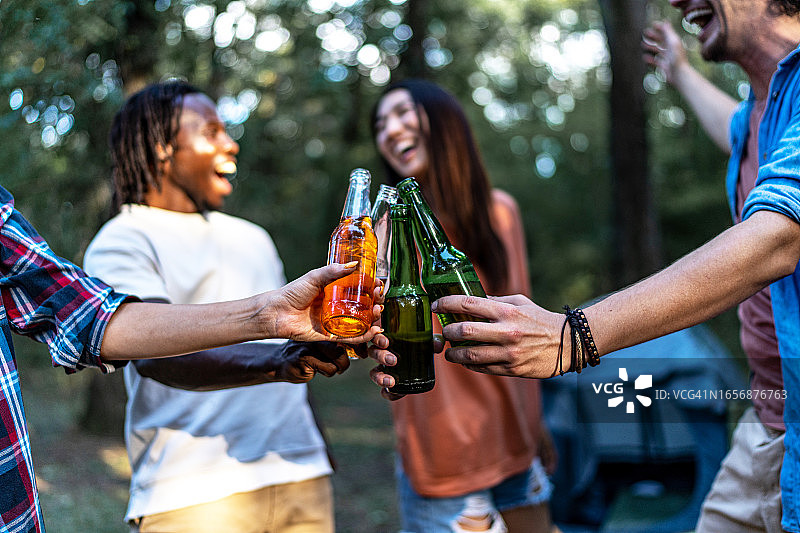 在森林里碰杯啤酒瓶的快乐朋友们图片素材