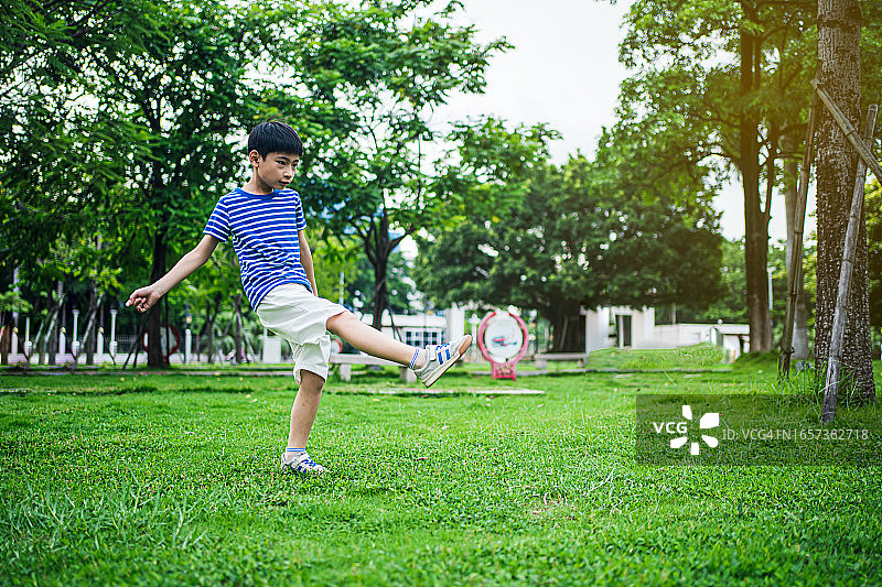 在公园里踢足球的亚洲男孩图片素材