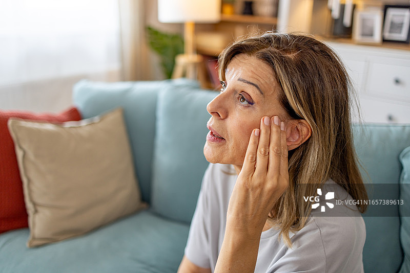 在家因耳痛而捂耳朵的年长女性图片素材