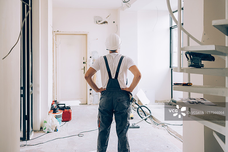 身份不明的建筑工双手叉腰，俯瞰他正在翻新的公寓图片素材