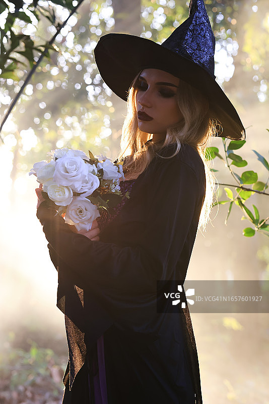 黑裙女巫在森林中手持白玫瑰图片素材