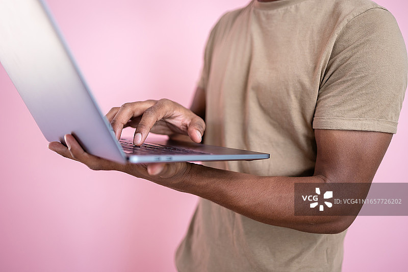 一名非裔美国男子在工作室拍摄中使用笔记本电脑的中段照片图片素材