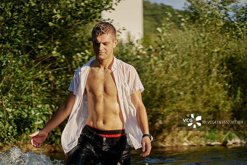 年轻男子解开衬衫，在河里戏水图片素材