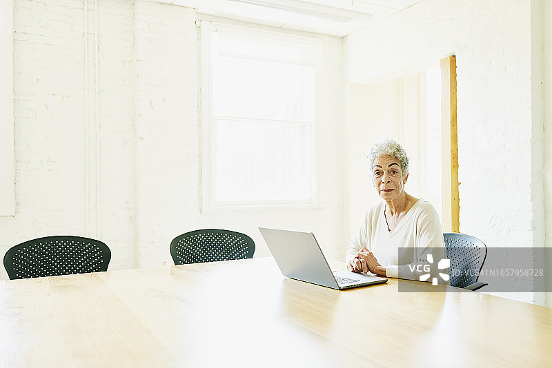 在办公室会议室工作的年长女商人图片素材