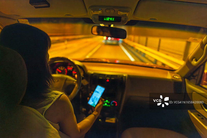 夜晚开车时手持手机的女人图片素材