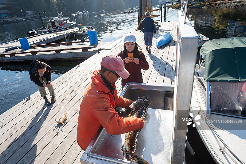 年长的亚洲男人教年轻人清洁鱼和捕蟹图片素材