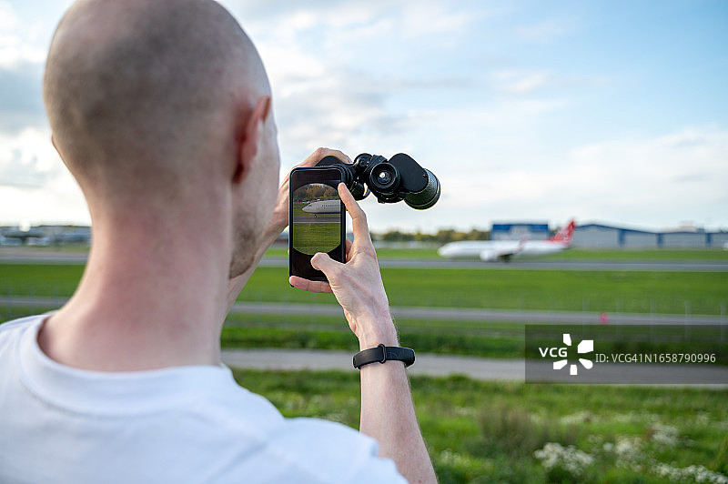 用双筒望远镜看飞机的男人图片素材