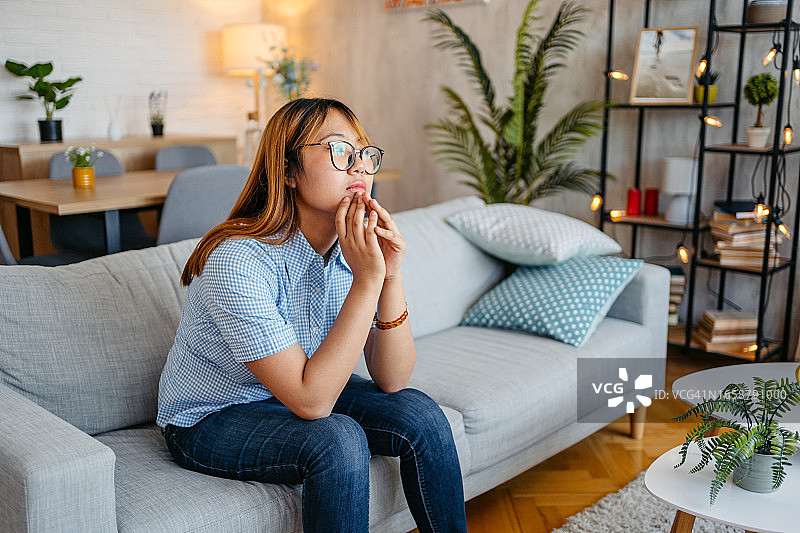 年轻沉思的女人独自坐在客厅图片素材