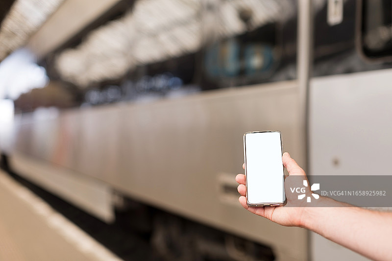 男人在火车旁拿着智能手机模型图片素材