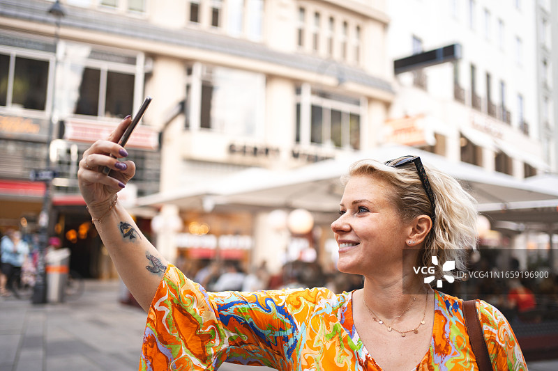 金发女人在探索维也纳市时用手机拍照图片素材