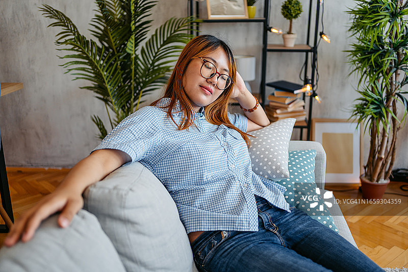 在舒适沙发上休息的年轻女人图片素材
