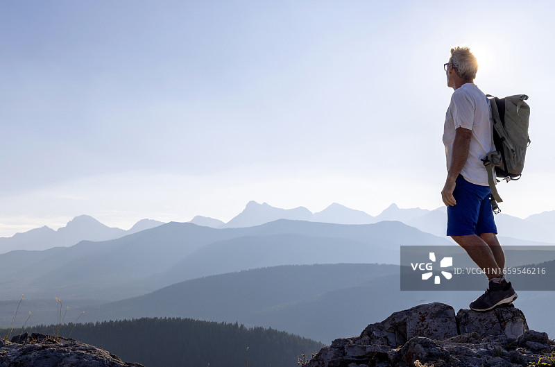 年长的男徒步旅行者到达山顶图片素材