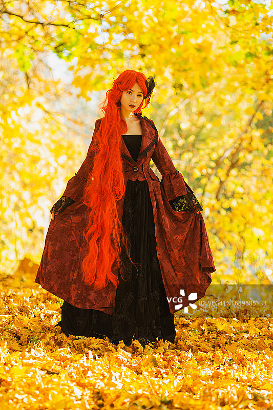 穿红色哥特风连衣裙的红发女人：万圣节风格图片素材