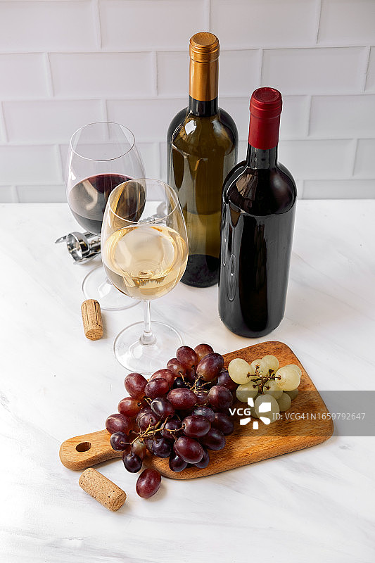 白葡萄酒杯、红葡萄酒杯、红葡萄酒瓶、白葡萄酒瓶和新鲜葡萄图片素材