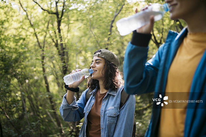 两个朋友在徒步期间休息喝水图片素材