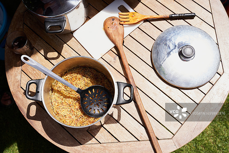 餐桌上的烹饪用具（如叉子、平底锅、汤锅、勺子、砧板等）的俯视照片，烹饪西班牙面条。餐饮概念。图片素材