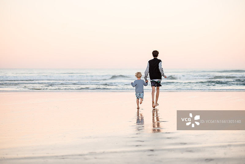 幼儿在海滩牵着哥哥的手图片素材
