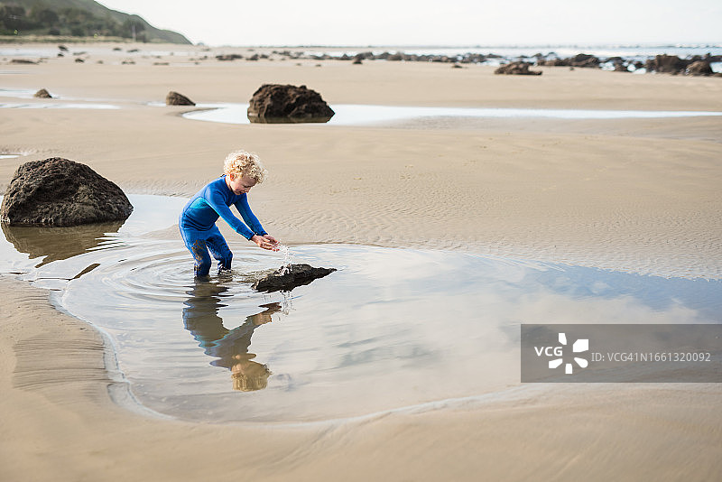 小男孩在新西兰海滩上戏水图片素材
