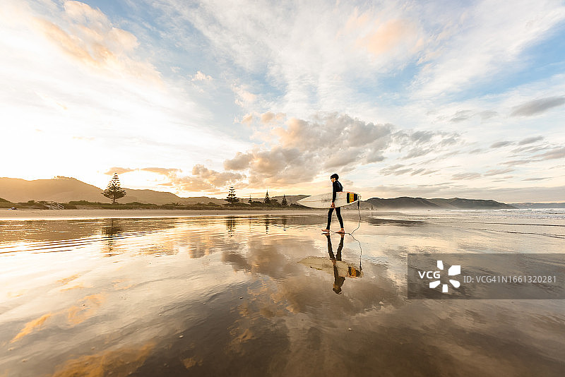 在海滩上拿着冲浪板行走的青少年图片素材