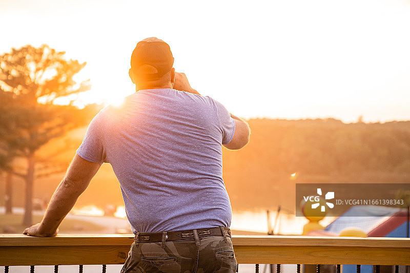 男人在湖边一边喝酒一边看日落图片素材