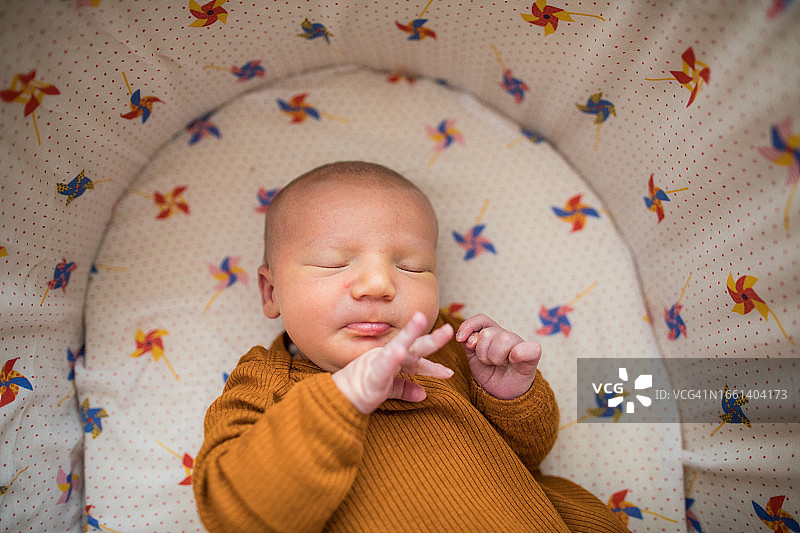 睡在床上，伸出小手指的新生婴儿图片素材