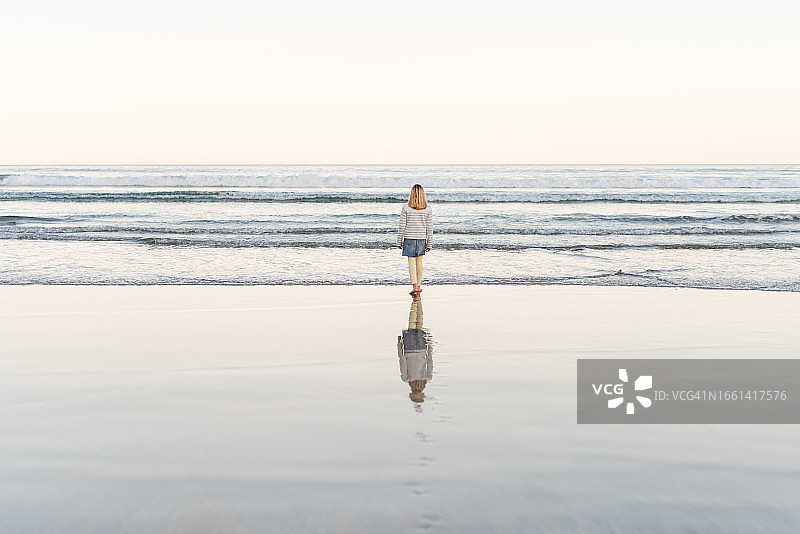 女孩走在有宁静倒影的海滩上图片素材