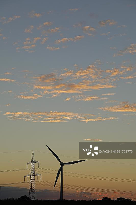 德国下萨克森州梅尔贝克，风力发电站和高压电塔的日落景观图片素材