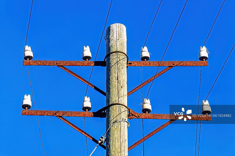 瑞典蓝天下带瓷绝缘子和电话线的旧电线杆图片素材