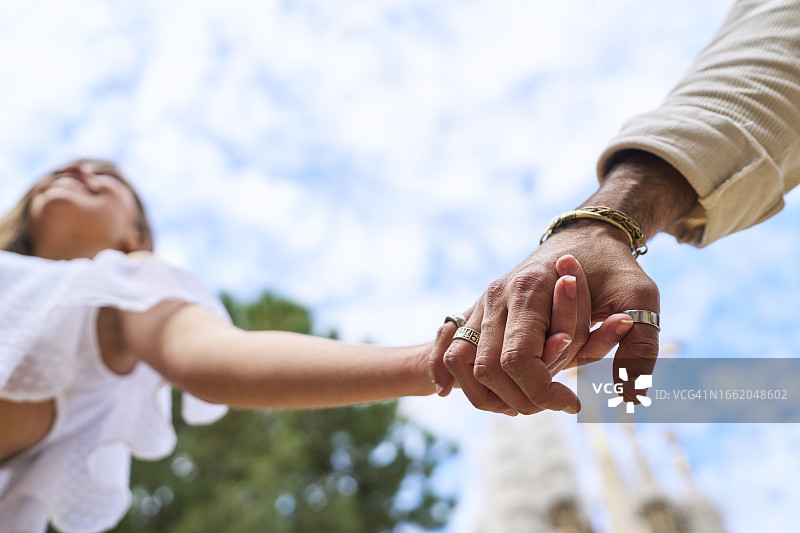 蓝天下，手牵手幸福的新娘和新郎（仰视）图片素材