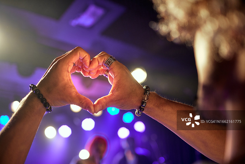 音乐厅紫色灯光下的心形手势图片素材