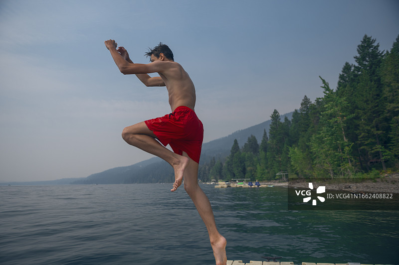 少年跃入风景优美的山间湖泊图片素材