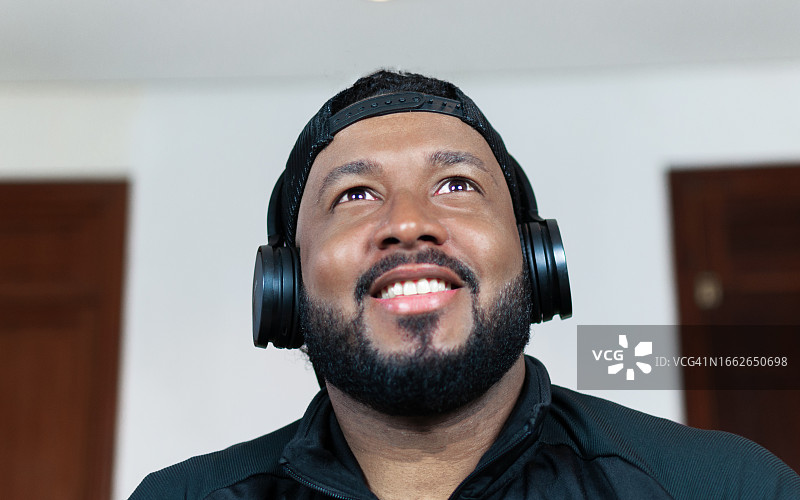 戴着耳机看向屏幕微笑的拉丁裔游戏玩家肖像图片素材