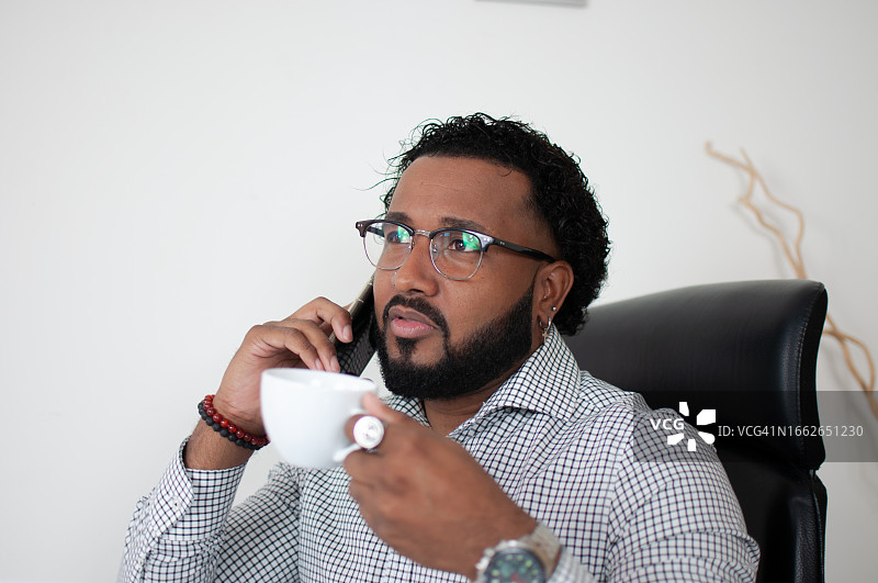 拉丁裔男商人喝咖啡打电话图片素材