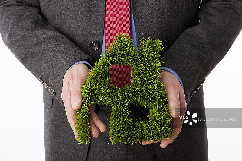 手拿草制房屋模型的人，特写图片素材