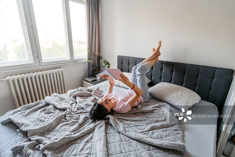 年轻女子早上在床上看笔记本图片素材