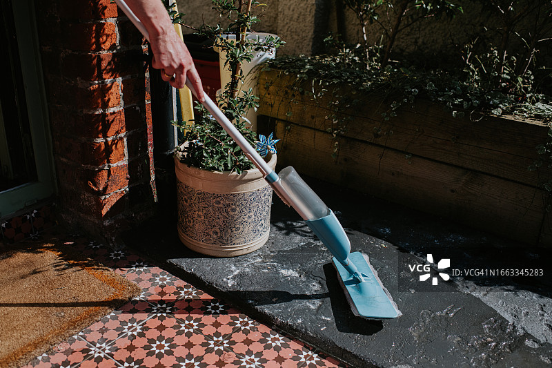 某人用喷雾拖把擦洗瓷砖门廊图片素材