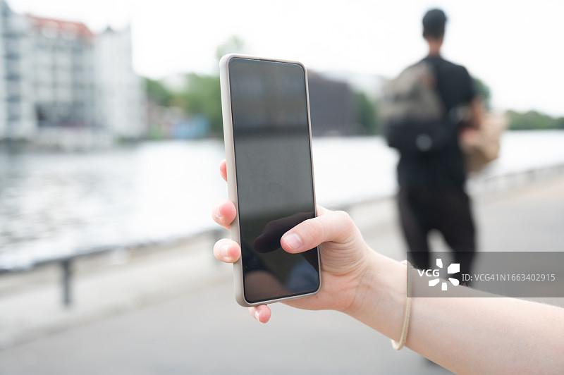 年轻女子在德国的河边使用手机图片素材