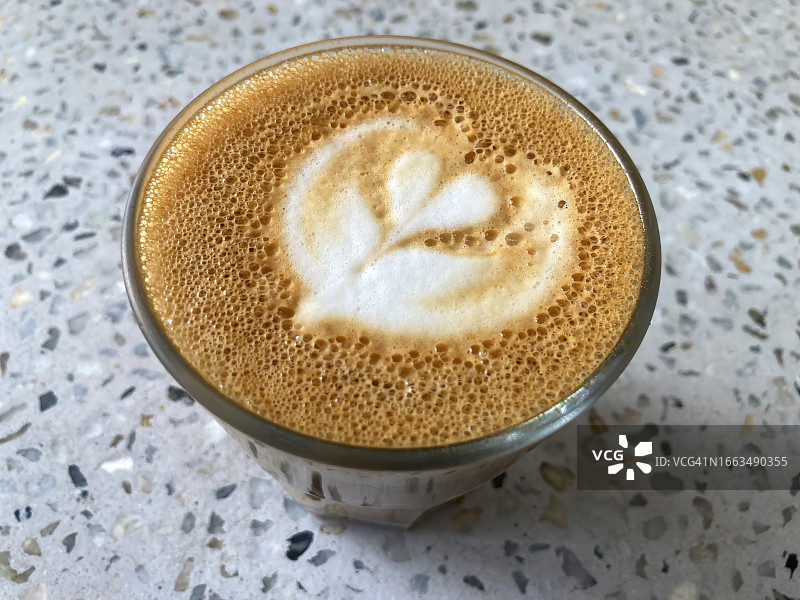 咖啡馆水泥桌上的郁金香图案拿铁图片素材