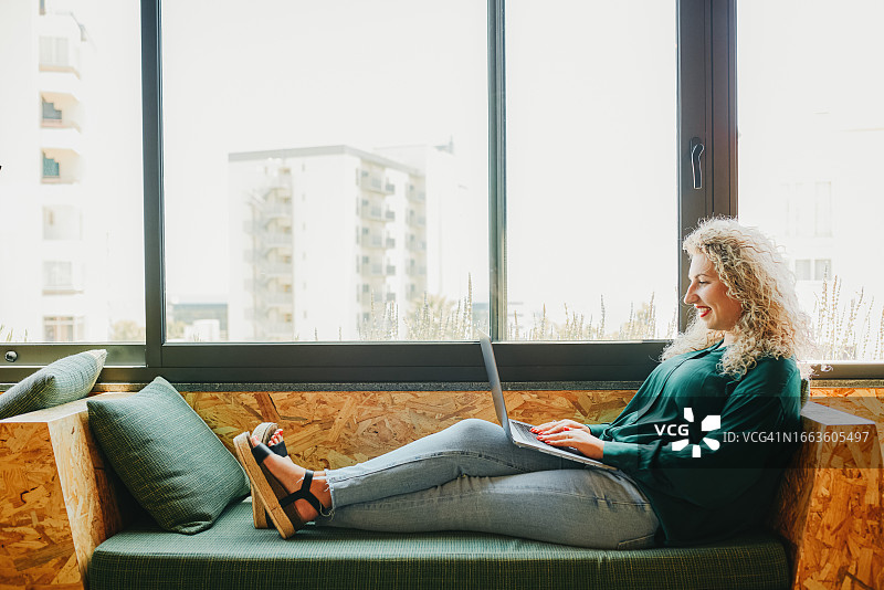 在休息区放松的拿着笔记本电脑的女商人侧视图图片素材