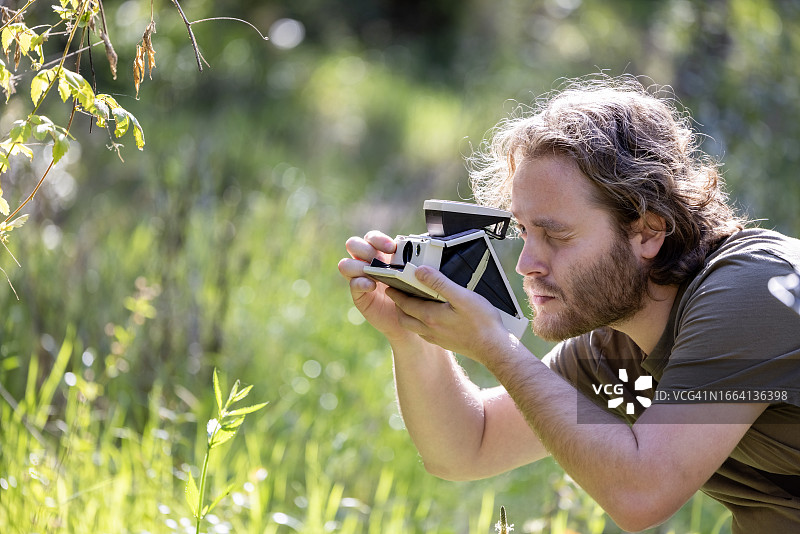 年轻男人用老式宝丽来相机拍照，背景有文案空间图片素材