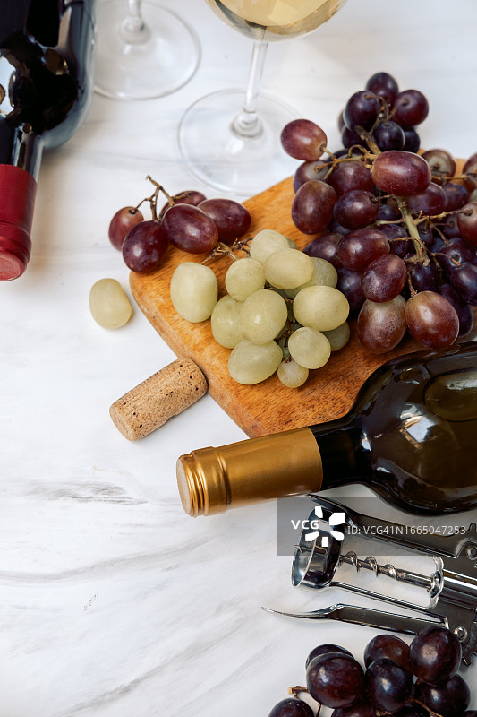 白桌上的法式白葡萄酒杯和意大利红葡萄酒杯，以及葡萄酒瓶和葡萄图片素材