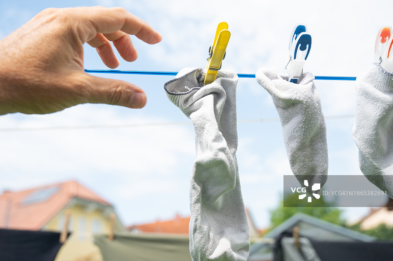 男子拿起晾在外面的一只干袜子图片素材